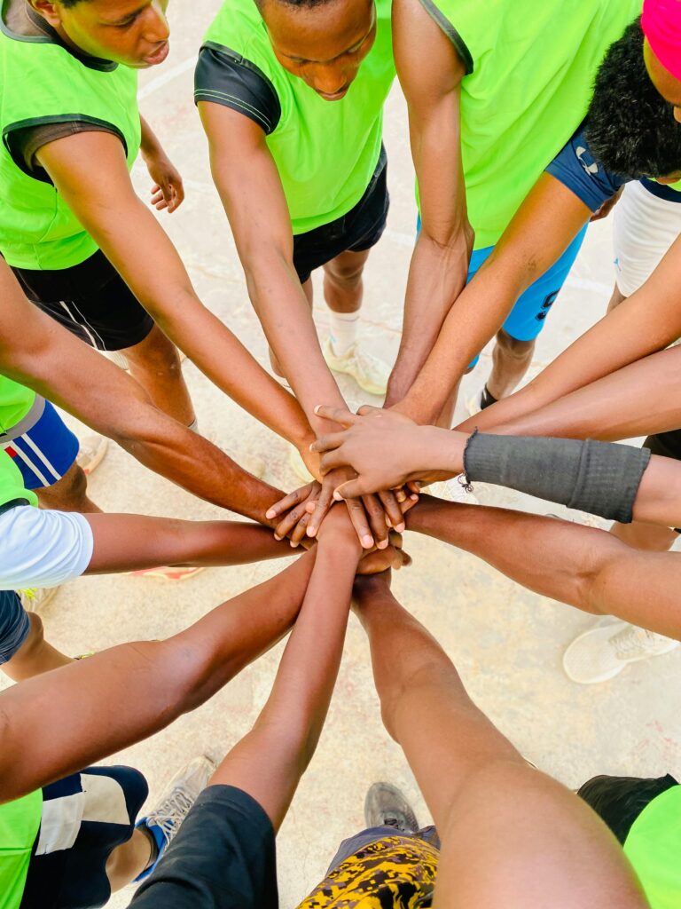 Group of team members stacking hands together, symbolizing community, collaboration, and welcoming new members