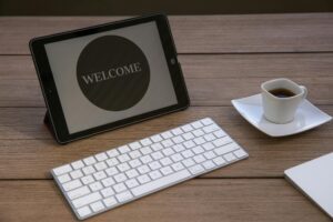 Tablet displaying ‘Welcome’ message on a desk with keyboard and coffee, symbolizing onboarding and new member welcome experience